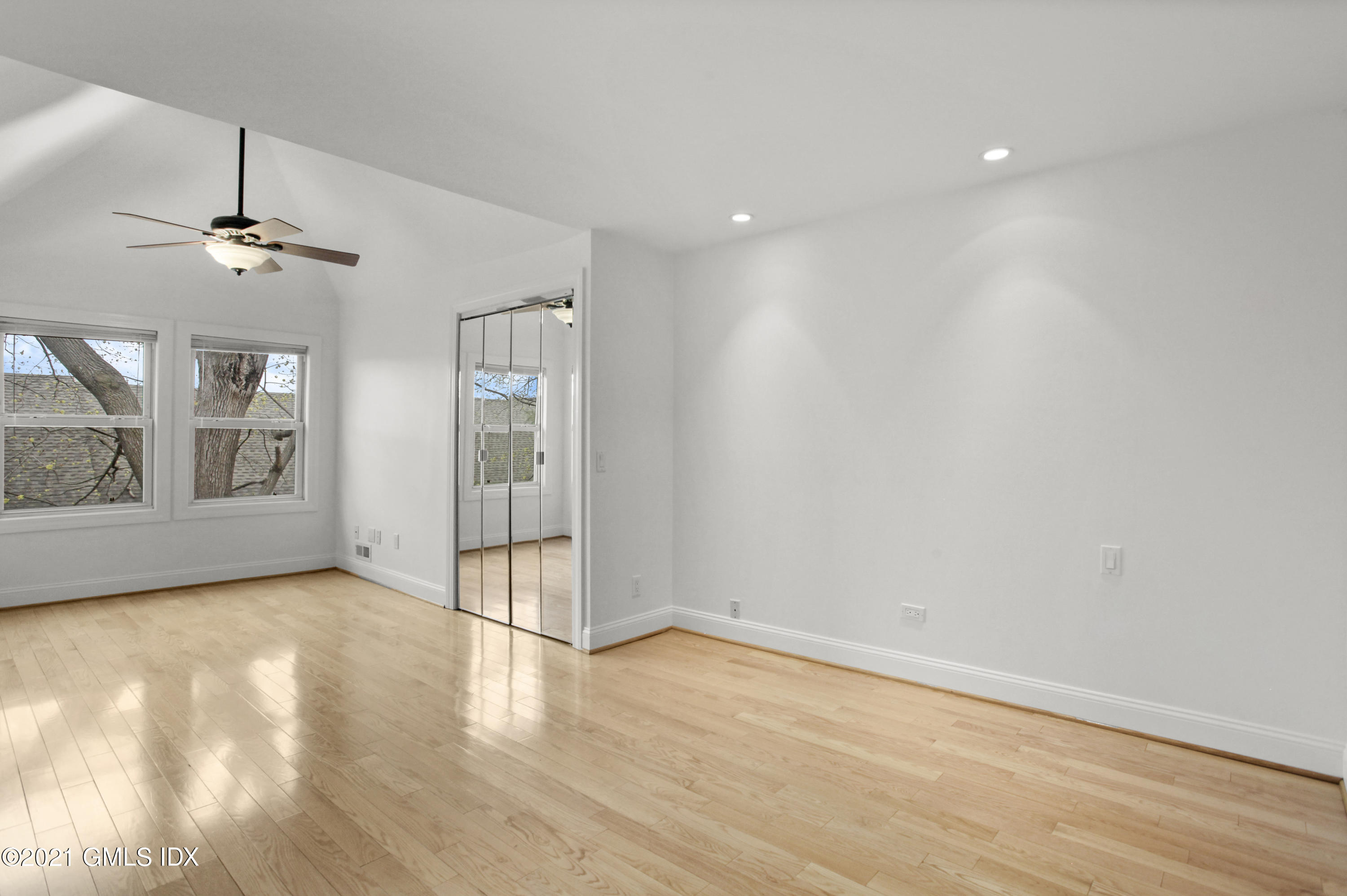 52 Bruce Park Drive, Unit B Greenwich, CT 06830 - Photo 17 of 20 an empty room with wooden floor chandelier and windows