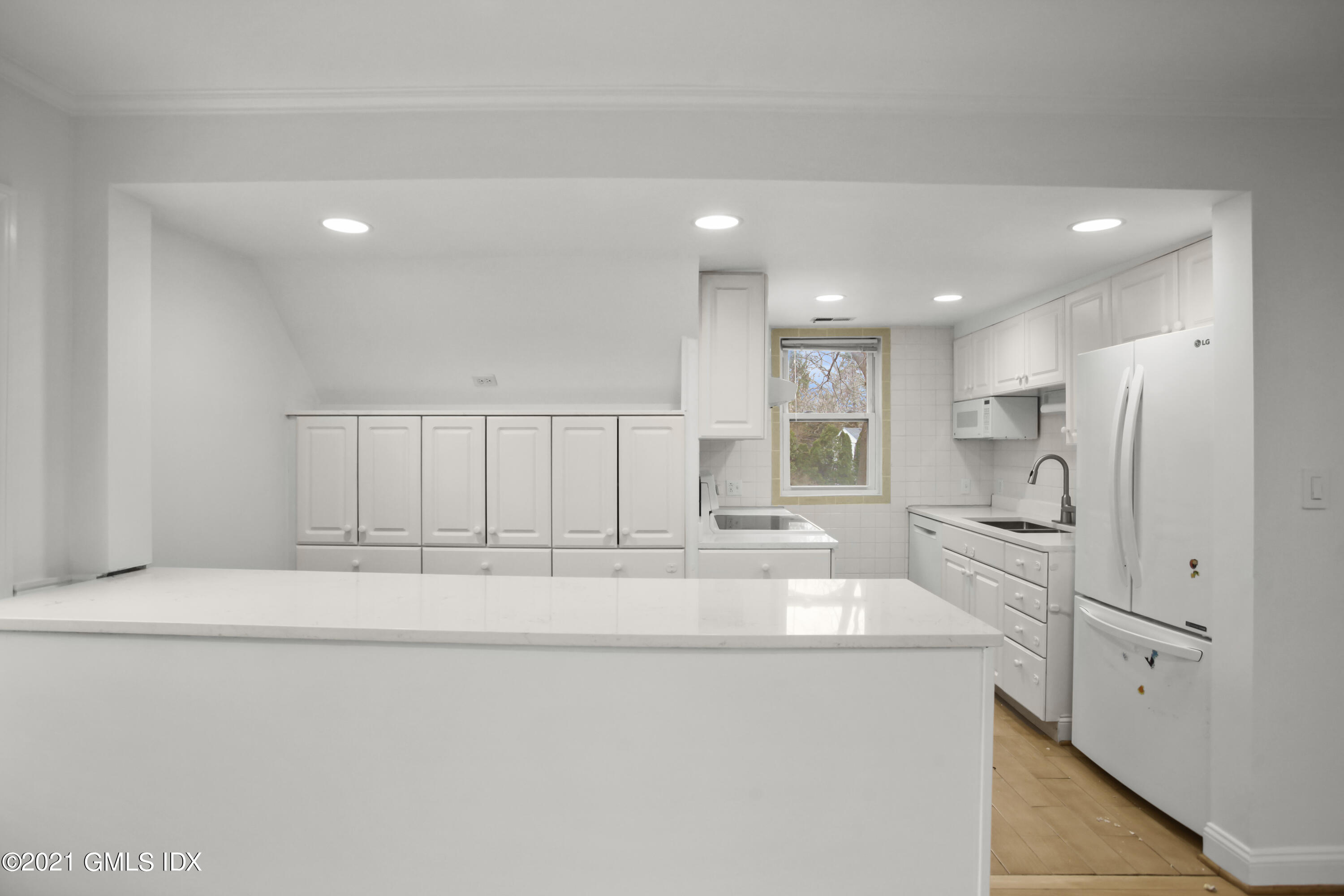 52 Bruce Park Drive, Unit B Greenwich, CT 06830 - Photo 5 of 20 a large white kitchen with white cabinets and stainless steel appliances