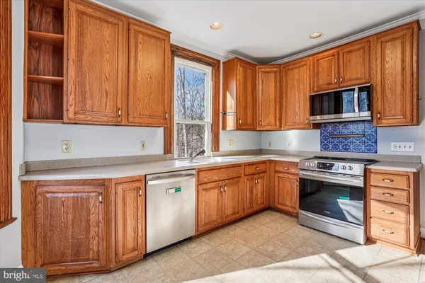 a kitchen with stainless steel appliances granite countertop a stove a sink and a microwave