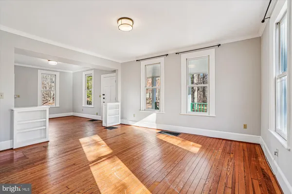 a view of an empty room with wooden floor and a window