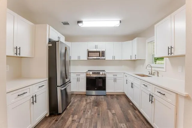 a kitchen with white cabinets and stainless steel appliances
