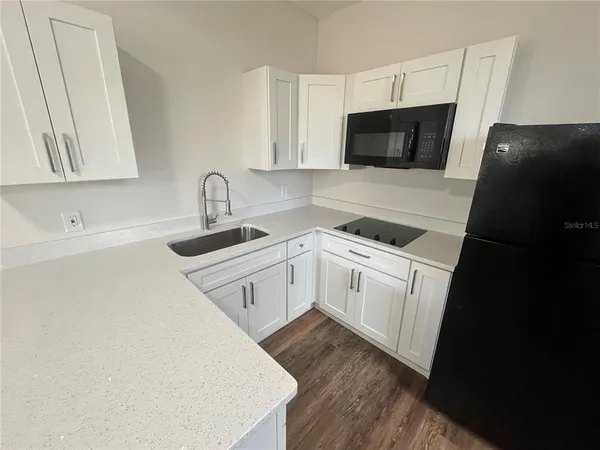 a white kitchen with sink a microwave and stove