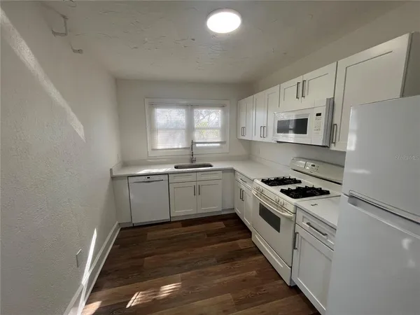 a kitchen with white cabinets and appliances
