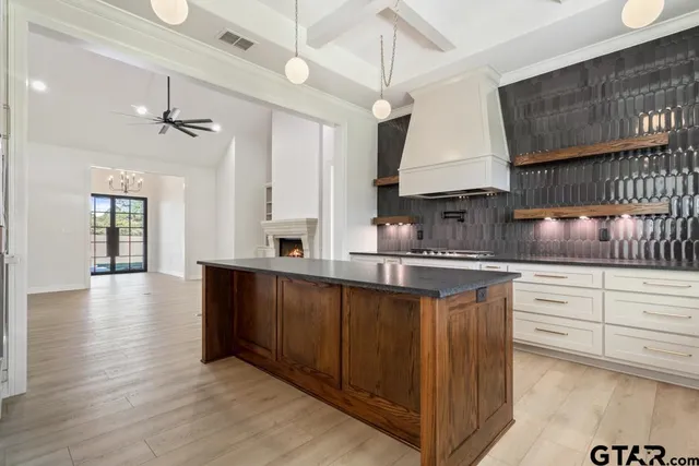 a kitchen with stainless steel appliances granite countertop a sink dishwasher a stove and white cabinets with wooden floor