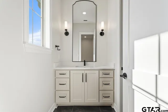a bathroom with a granite countertop sink and a mirror