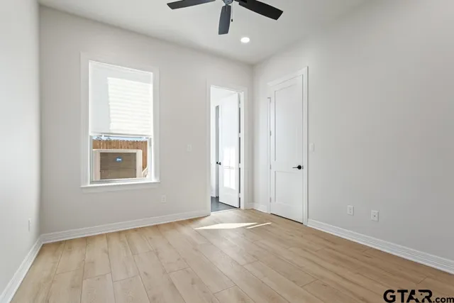 an empty room with wooden floor chandelier fan and windows