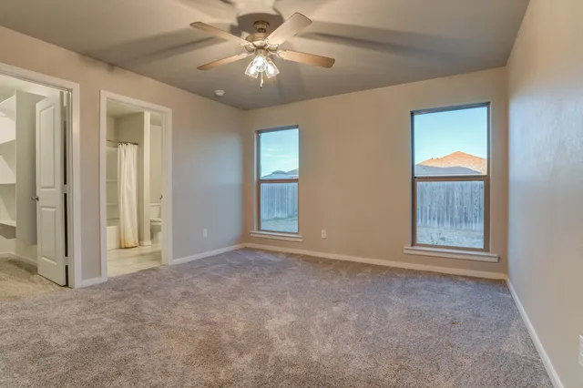 an empty room with windows and fan