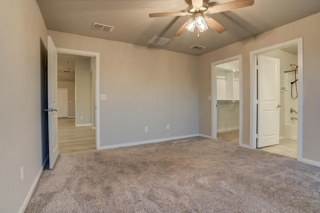 a view of an empty room and chandelier fan