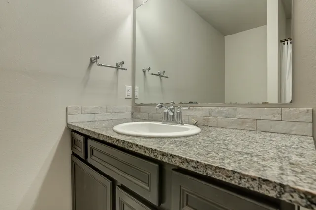 a bathroom with a granite countertop sink and a mirror