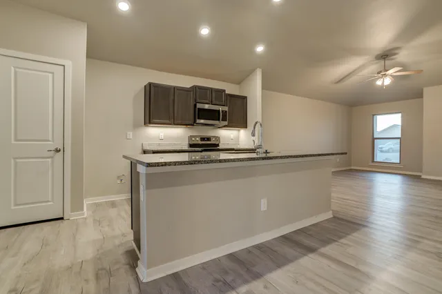 a kitchen with granite countertop a refrigerator and a stove top oven