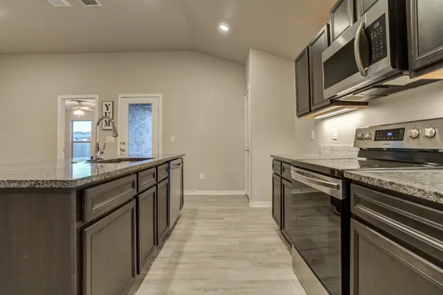 a kitchen with stainless steel appliances granite countertop a sink and a stove