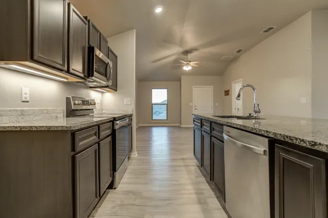 a kitchen with stainless steel appliances granite countertop lots of counter top space and wooden floor