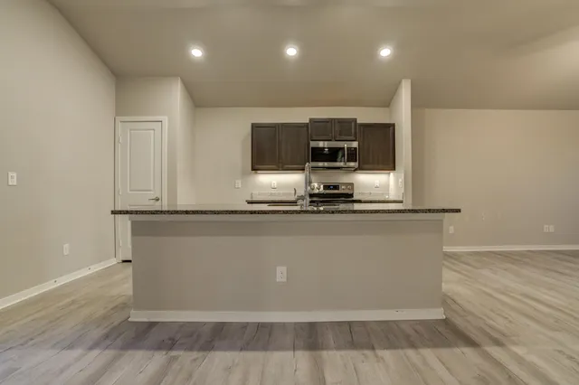 a room with kitchen island stainless steel appliances a sink and a fireplace
