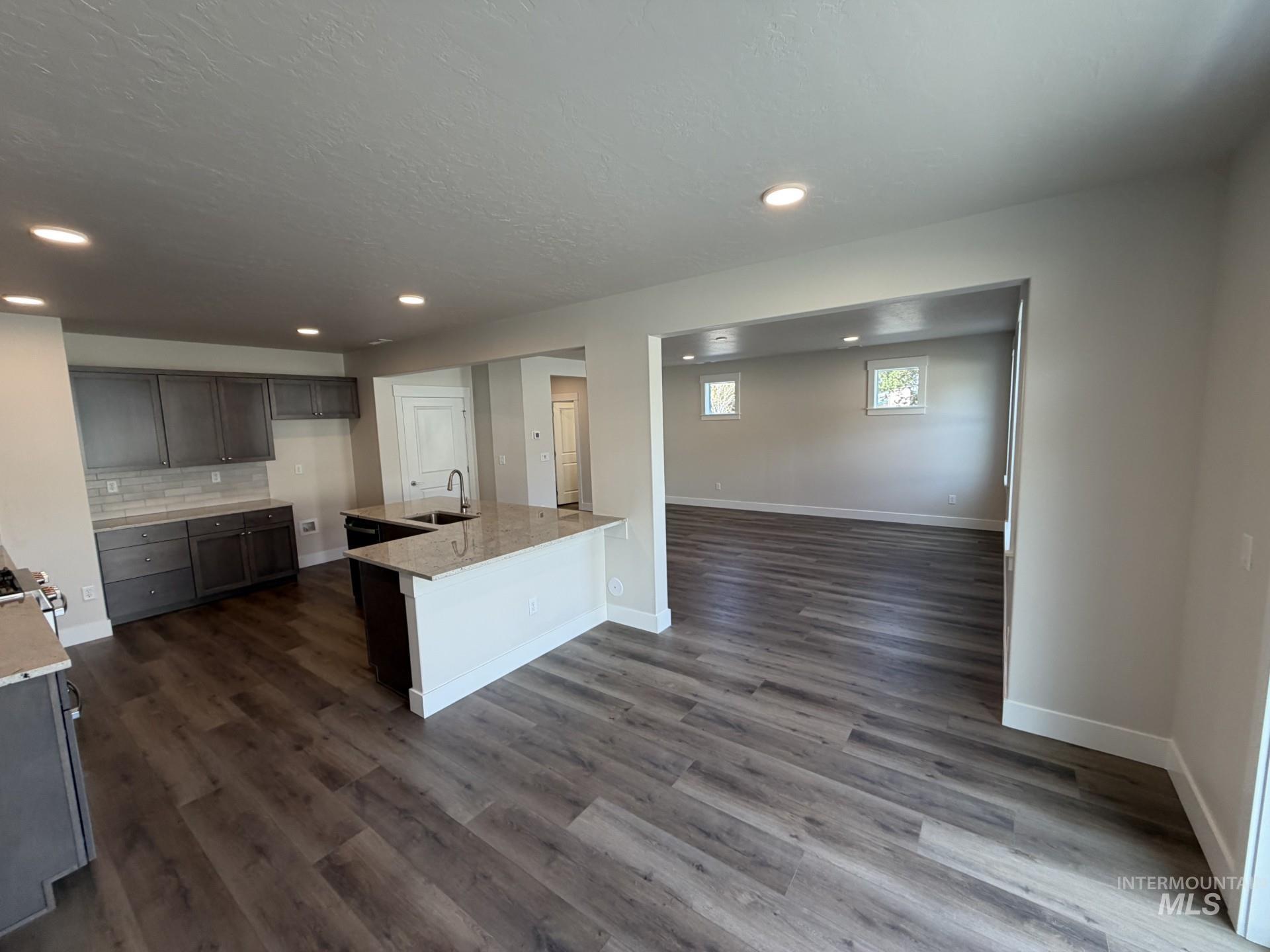 Tbd East Fitz Roy Street, Unit TALENT Kuna, ID 83634 - Photo 3 of 23 Kitchen with light stone counters, dark wood finished floors, dark wood finish cabinetry, decorative backsplash, and recessed lighting