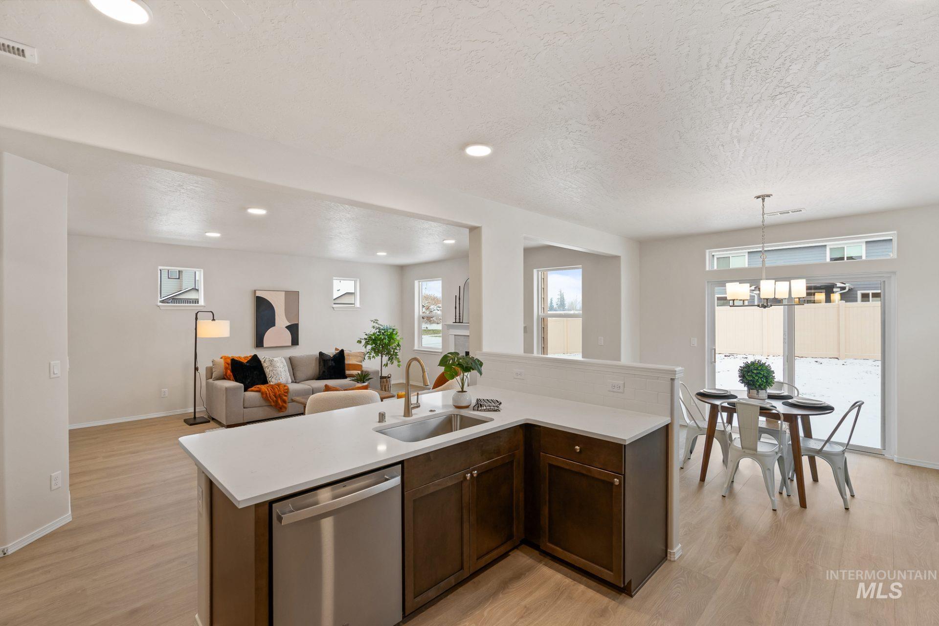 Tbd East Fitz Roy Street, Unit TALENT Kuna, ID 83634 - Photo 22 of 23 Kitchen with dark wood finish cabinets, stainless steel dishwasher, open floor plan, light wood-style floors, and suspended lighting