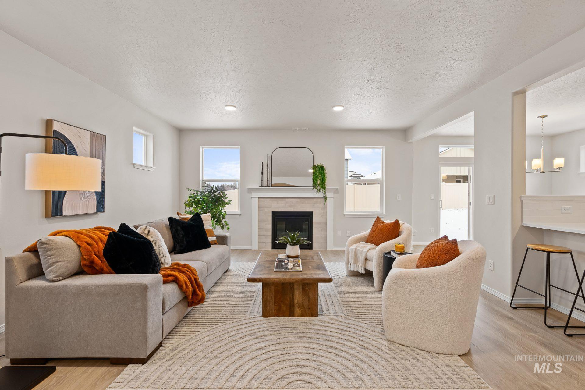 Tbd East Fitz Roy Street, Unit TALENT Kuna, ID 83634 - Photo 7 of 23 Living room with light wood finished floors, a textured ceiling, a tile fireplace, and suspended lighting