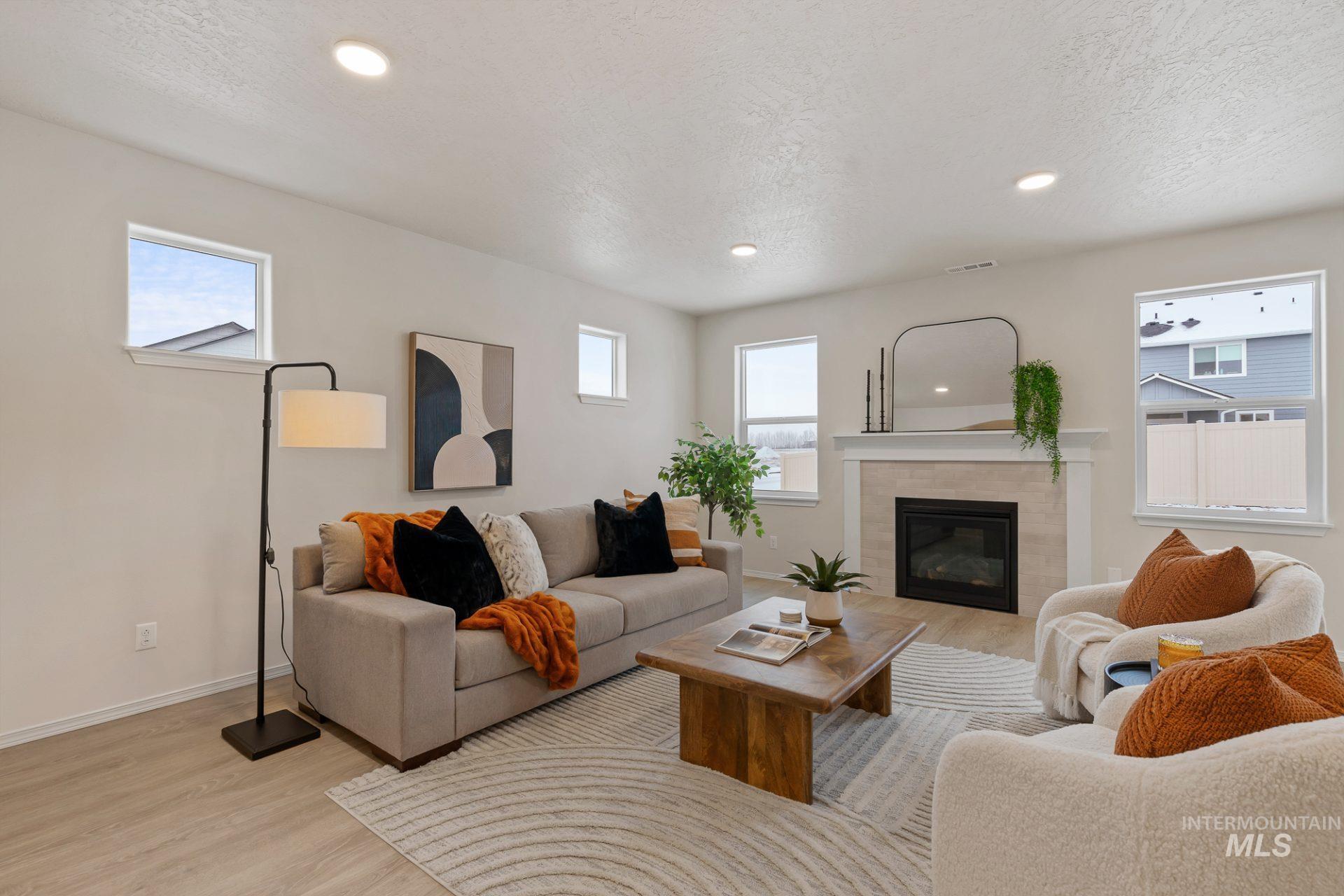Tbd East Fitz Roy Street, Unit TALENT Kuna, ID 83634 - Photo 8 of 23 Living area with light wood-type flooring, recessed lighting, a tiled fireplace, plenty of natural light, and a textured ceiling