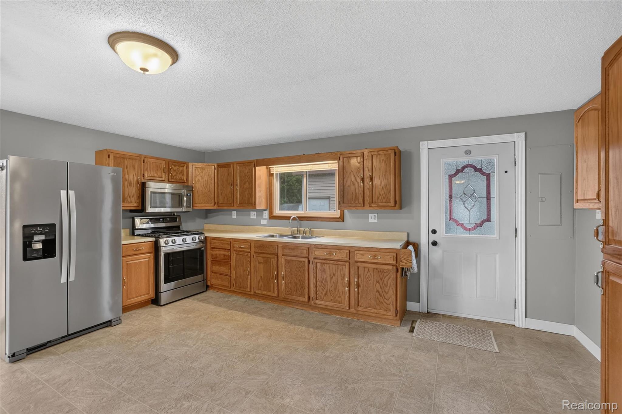 10977 Maple Road Birch Run, MI 48415 - Photo 13 of 49 Kitchen featuring wood cabinetry, stainless steel appliances, a double basin sink, and tile flooring
