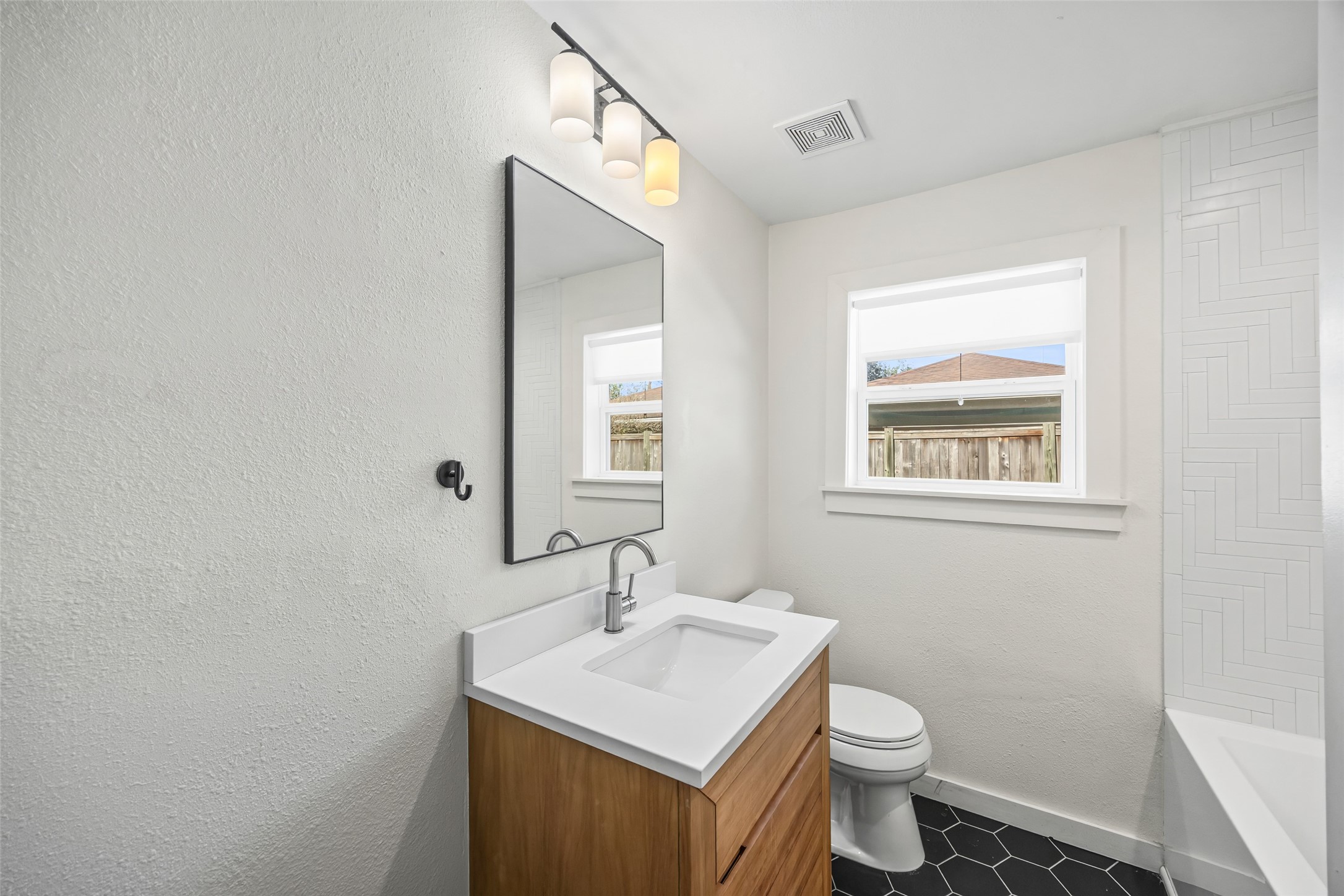 9715 Greenwillow Street Houston, TX 77096 - Photo 18 of 31 a bathroom with a toilet a sink a mirror and a window