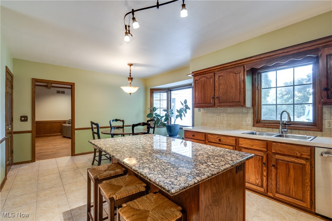 3465 Bancroft Road Akron, OH 44333 - Photo 20 of 50 Kitchen featuring a kitchen bar, a center island, dishwasher, tasteful backsplash, and hanging light fixtures