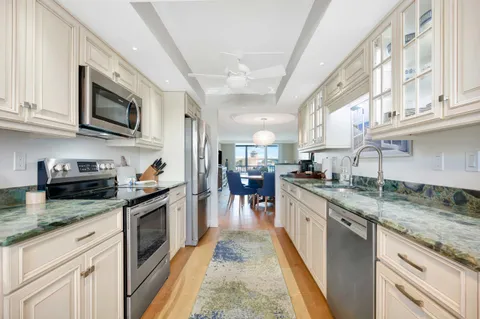 a kitchen with stainless steel appliances granite countertop a stove top oven a sink dishwasher and a microwave oven with white cabinets