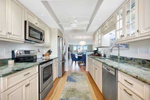 a kitchen with stainless steel appliances granite countertop a stove top oven a sink dishwasher and a microwave oven with white cabinets