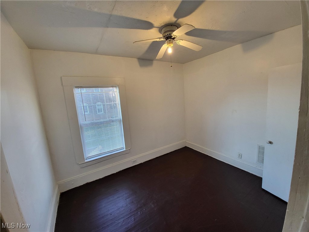 Unfurnished room with dark wood-type flooring and ceiling fan