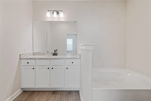 a bathroom with a granite countertop sink and a bathtub
