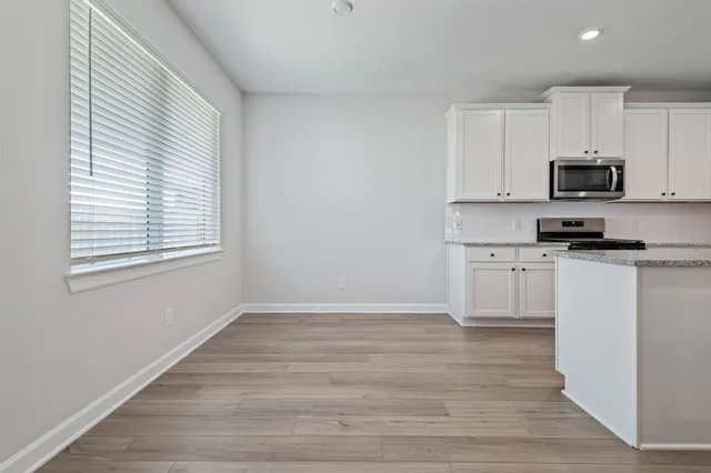 a kitchen with white cabinets appliances a sink and a window