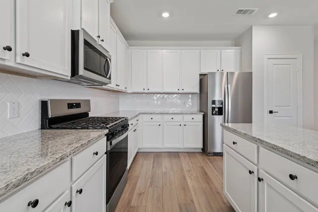 a kitchen with stainless steel appliances granite countertop cabinets and a wooden floor