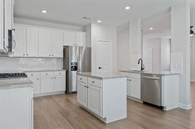 a kitchen with white cabinets and stainless steel appliances