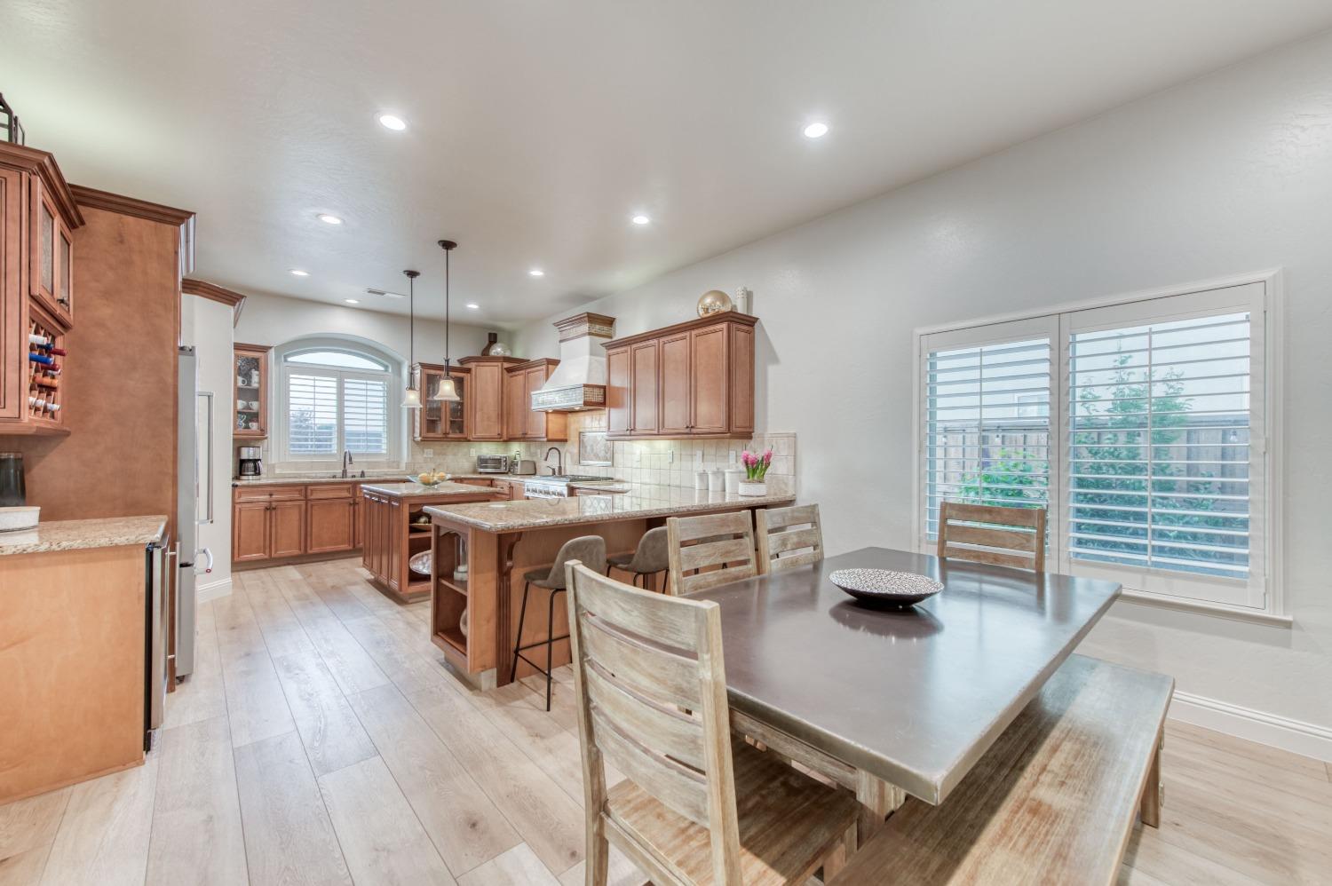 1674 North Cindy Avenue Clovis, CA 93619 - Photo 10 of 46 a kitchen with stainless steel appliances granite countertop a refrigerator a sink dishwasher a stove and a dining table with wooden floor
