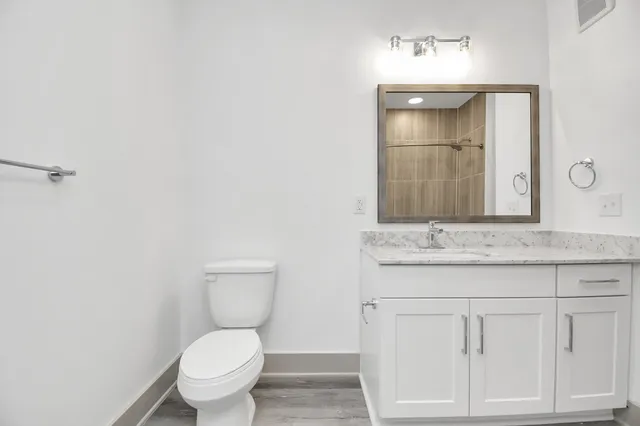 a bathroom with a granite countertop toilet sink and mirror