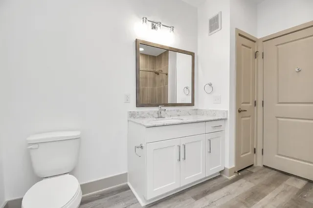 a bathroom with a granite countertop toilet sink and mirror