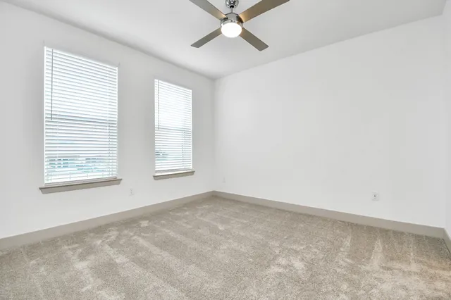 an empty room with a window and a ceiling fan