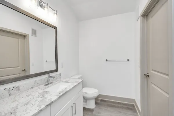 a bathroom with a granite countertop sink toilet and mirror