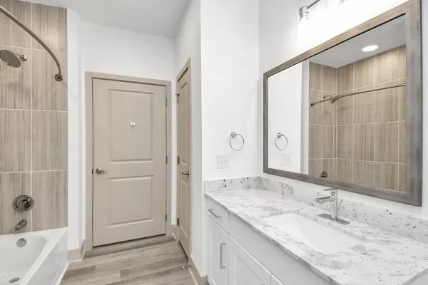 a bathroom with a granite countertop sink a mirror and a bathtub