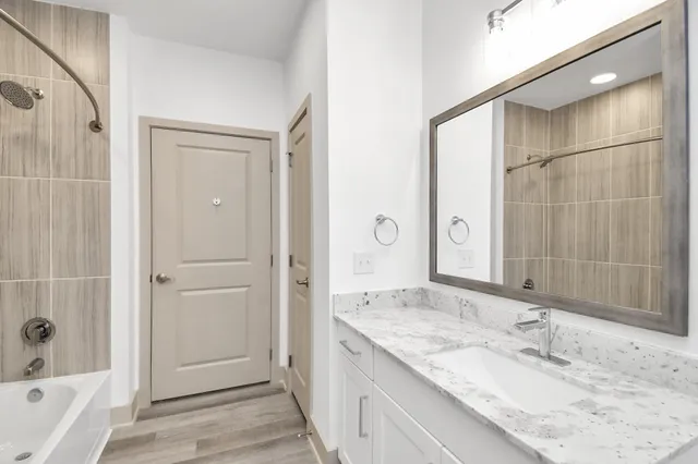 a bathroom with a granite countertop sink a mirror and a bathtub