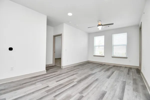 an empty room with wooden floor chandelier and windows