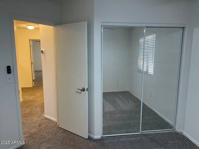 an empty room with a chandelier fan and windows