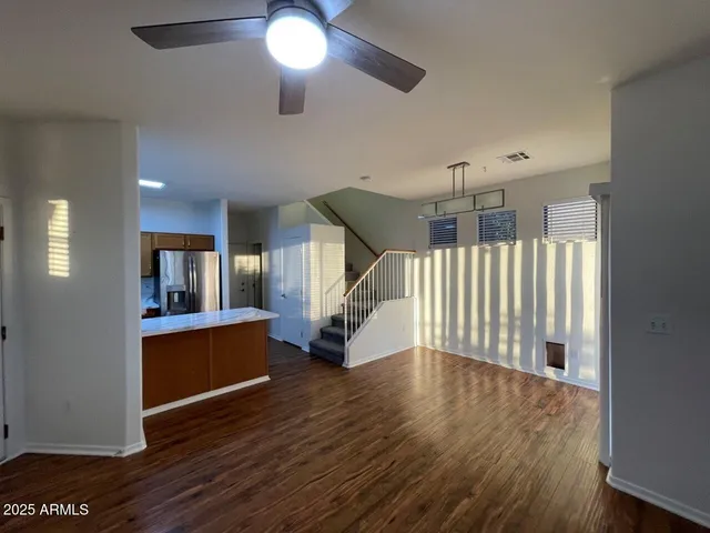 a view of living room with kitchen island stainless steel appliances wooden floor and windows