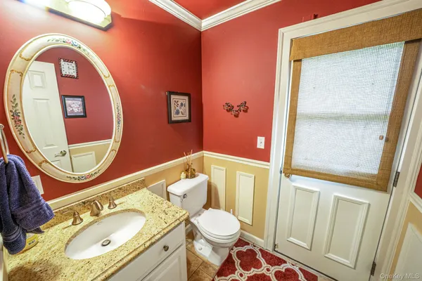 a bathroom with a granite countertop toilet a sink and a mirror