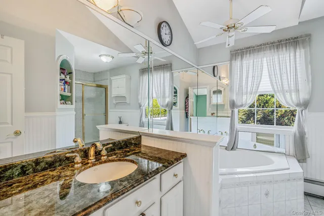 a bathroom with a granite countertop sink a mirror and a bathtub