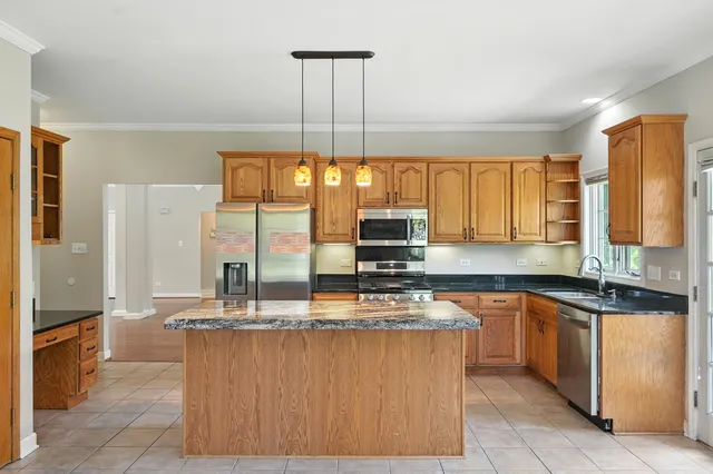 a kitchen with kitchen island granite countertop a sink a counter top space appliances and cabinets