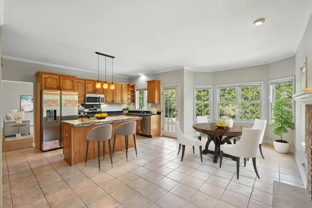 a dining room with stainless steel appliances a table and chairs next to a large window
