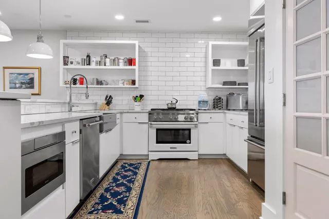 a kitchen with a white stove top oven and white cabinets with wooden floor