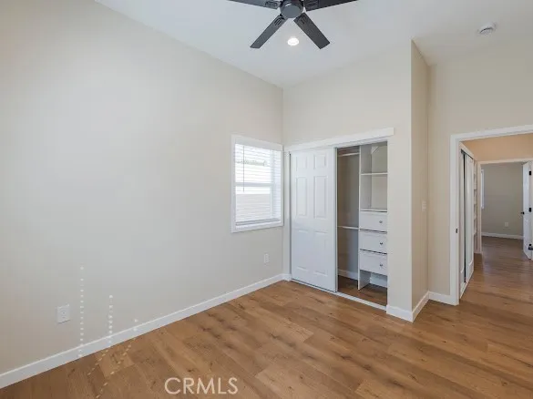 an empty room with wooden floor and ceiling fan
