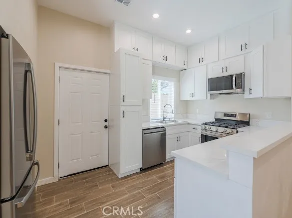 a kitchen with stainless steel appliances granite countertop white cabinets granite counter tops and a hard wood floors