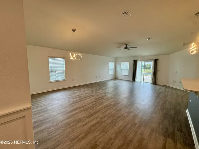 a view of an empty room with window and wooden floor