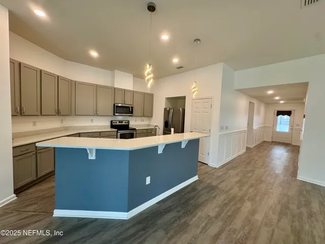 a kitchen with stainless steel appliances granite countertop a stove a refrigerator a sink dishwasher and a oven with wooden floor